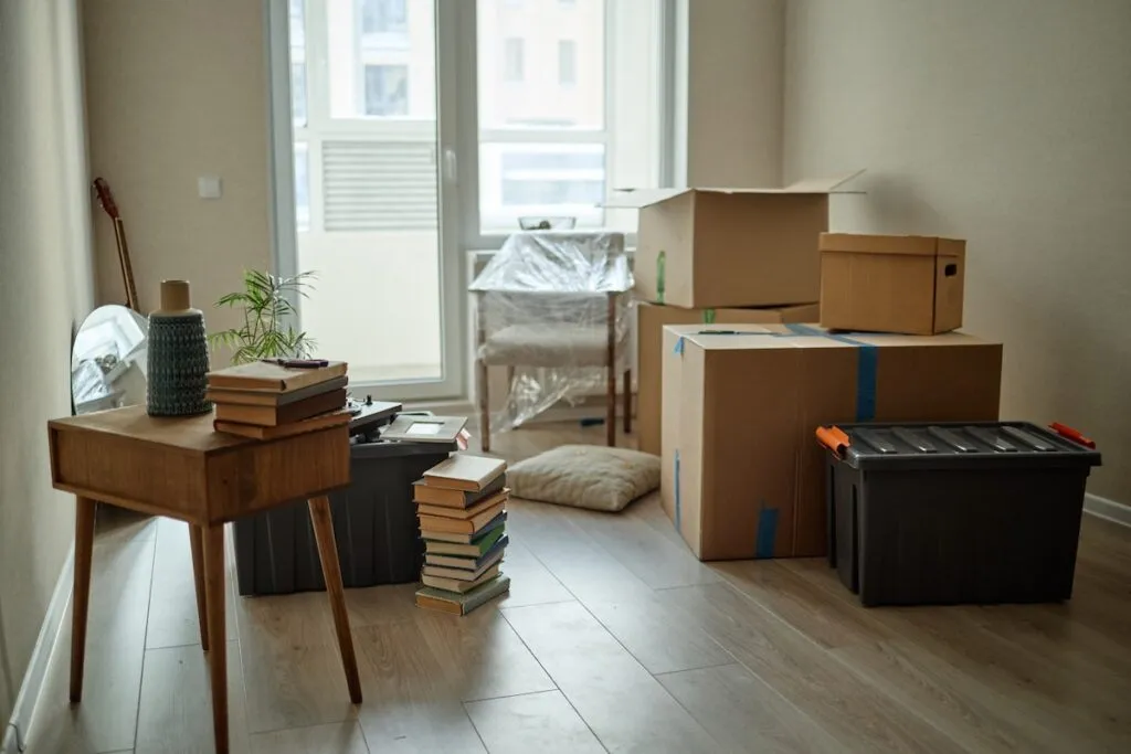 a room mid-downsizing with packed moving boxes, storage bins, and stacked books, estate downsizing in Winchester VA