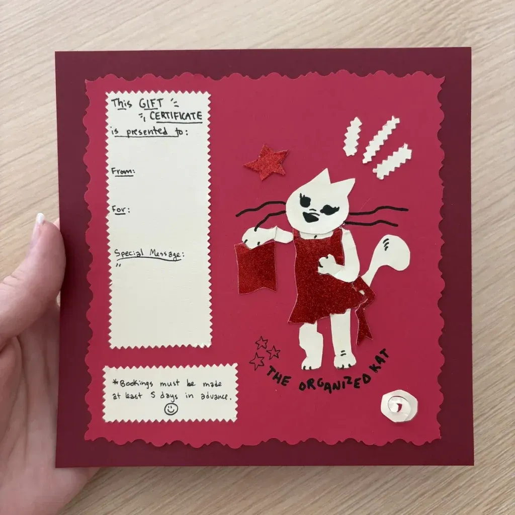 Hand-cut paper gift certificate for The Organized Kat professional organizing services, held in hand, Winchester VA