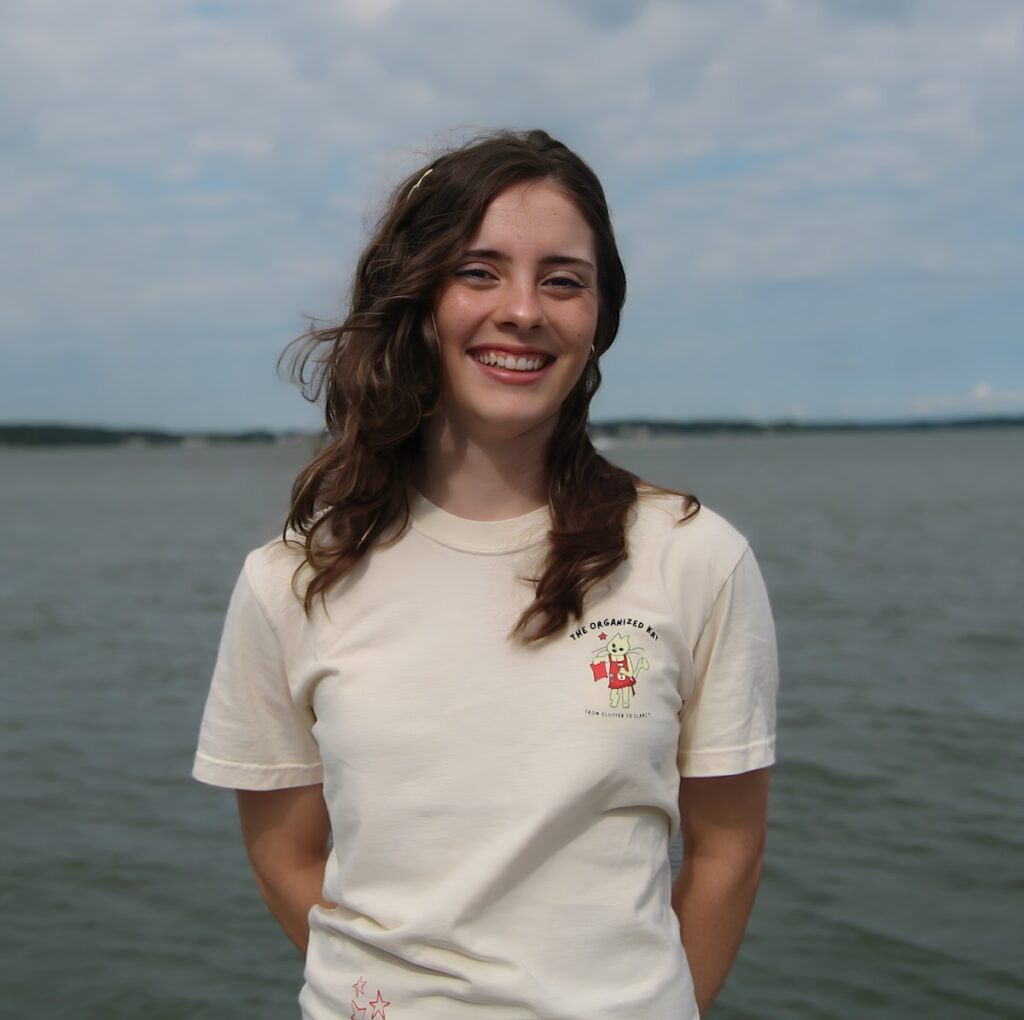 Eve, owner of The Organized Kat, standing on a dock in a branded t-shirt, professional home organizer serving Winchester VA