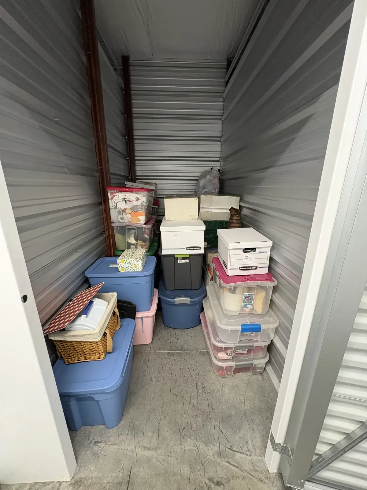 Organized self-storage unit in Winchester, VA with labeled bins and banker's boxes stacked neatly along the wall